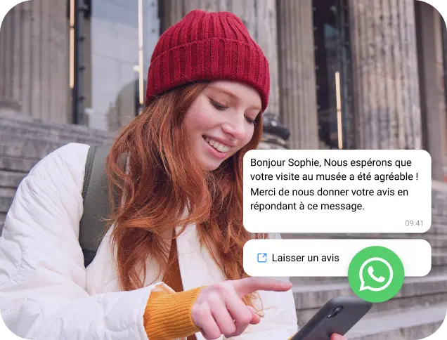 Une jeune femme portant une casquette rouge lit un message professionnel sur WhatsApp sur son téléphone.