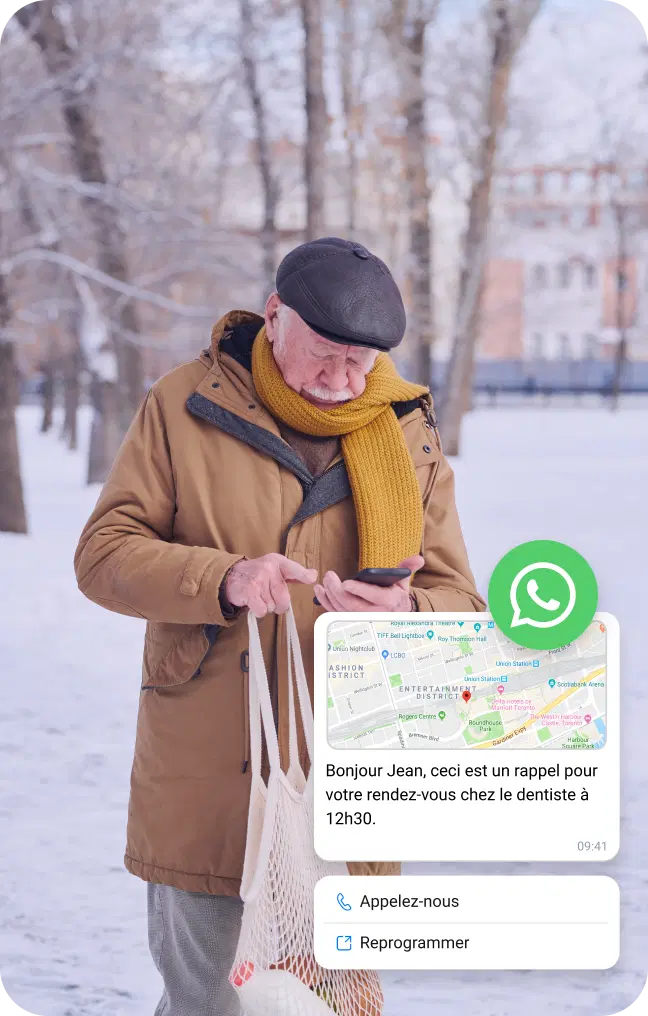 Un homme âgé, dans la neige, consulte son téléphone pour connaître l'emplacement via un message WhatsApp professionnel.