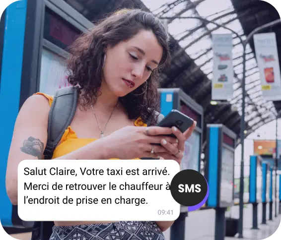 Une jeune fille avec un sac à dos attend à la station et vérifie un SMS concernant l'arrivée de son taxi.