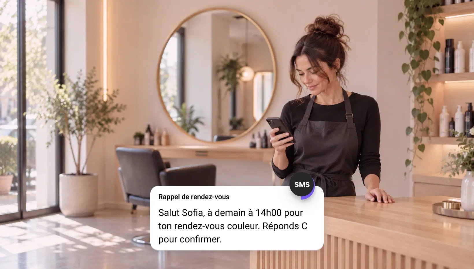 Propriétaire d’un salon lisant un rappel de rendez-vous par SMS sur son téléphone