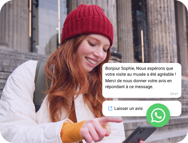 Jeune femme portant une casquette rouge lisant un message professionnel WhatsApp sur son téléphone.