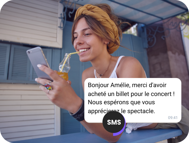 Jeune femme buvant un jus dans la rue consultant la confirmation de son billet de concert par SMS.